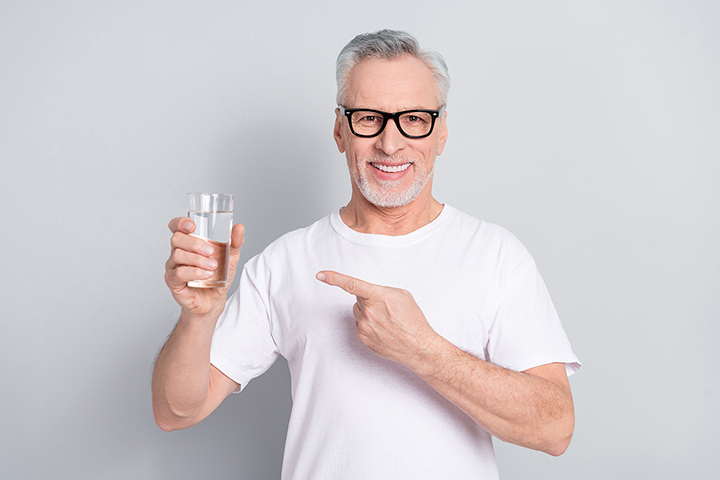 Photo of positive friendly person indicate finger demonstrate water glass isolated on grey color background.