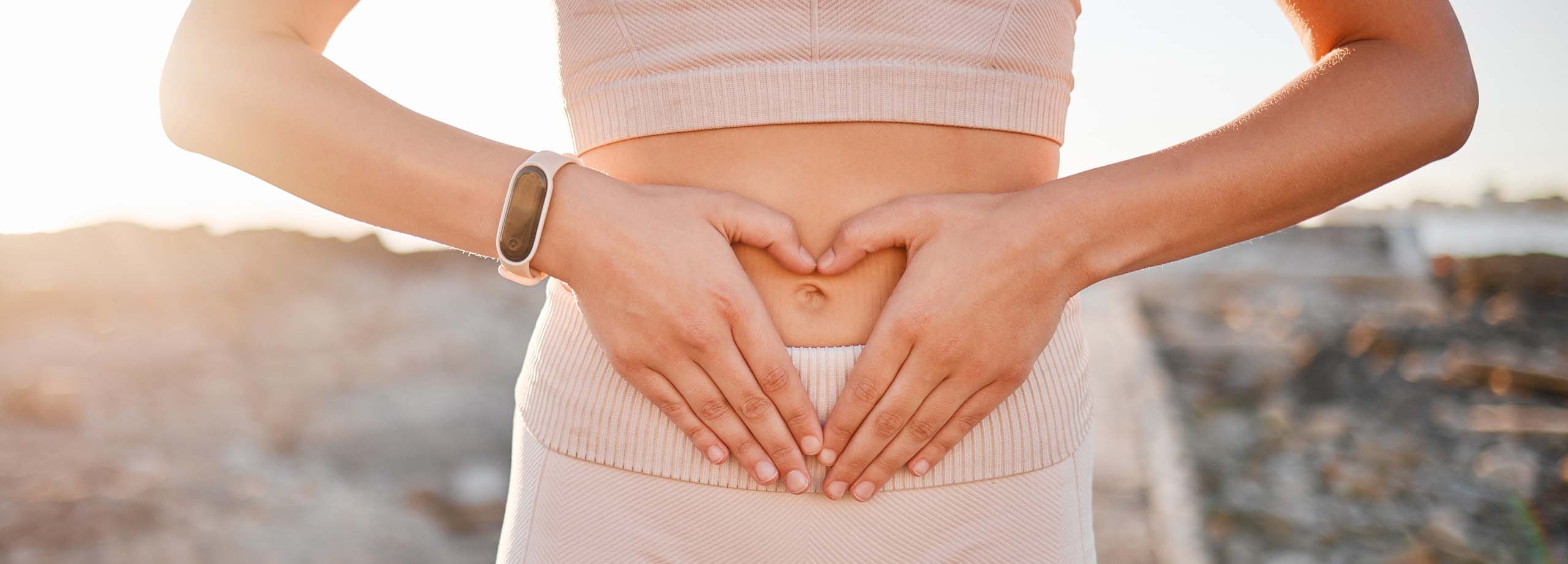 Woman, heart and hands on stomach for fitness, weightloss diet or holistic gut wellness. Closeup female abdomen, love fingers or belly emoji of body digestion, skincare and healthy exercise in nature.