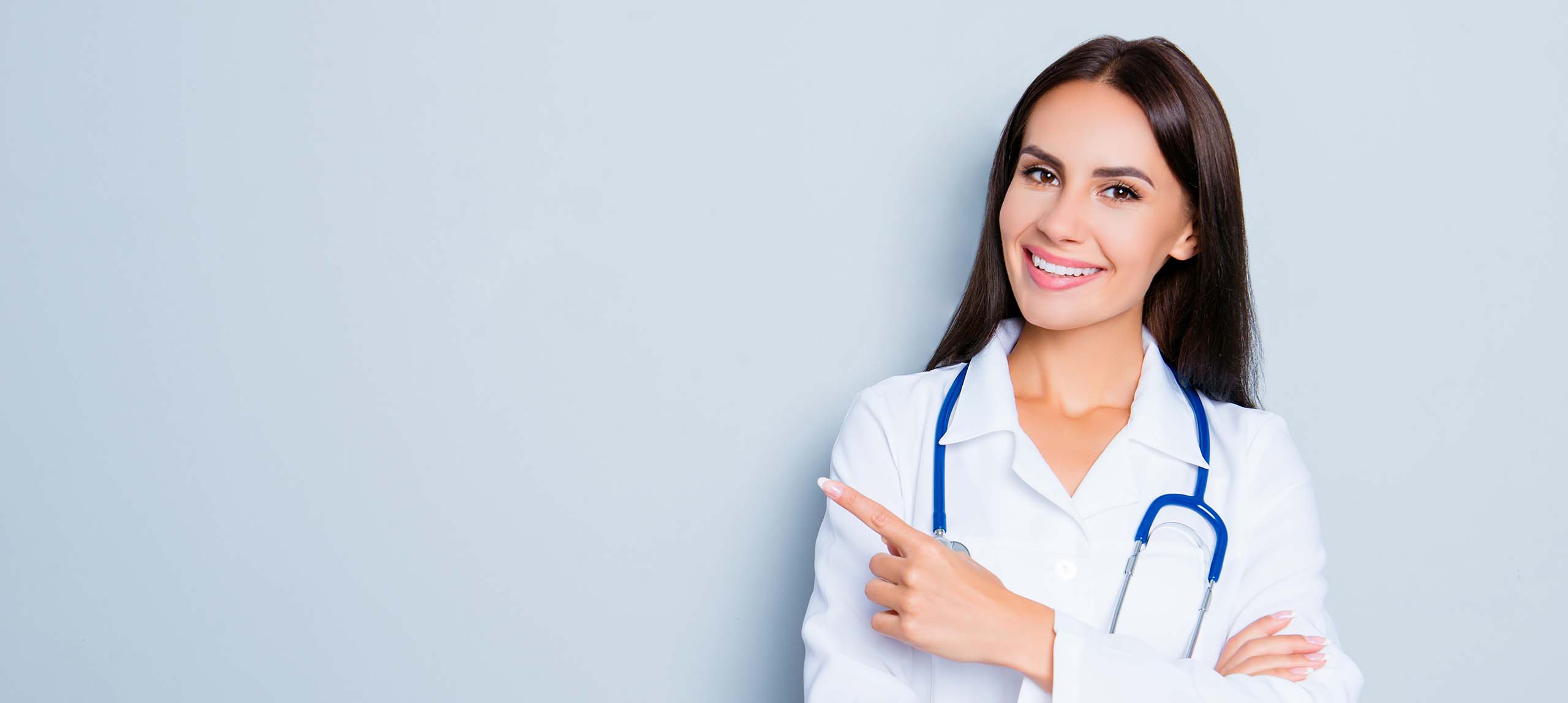 Smiling happy doctor pointing with finger on blue background